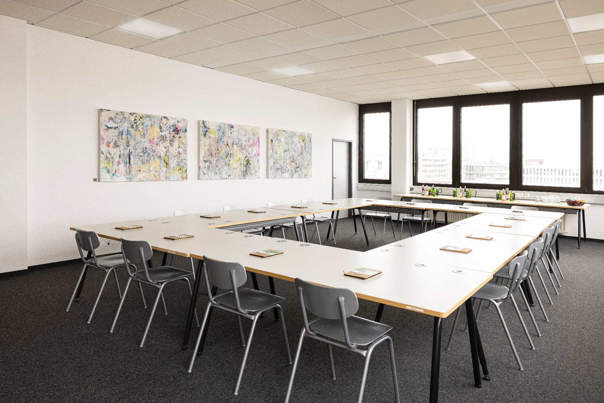 Conference Room mit U-förmiger Tischanordnung, grauen Stühlen und Kunst an der Wand