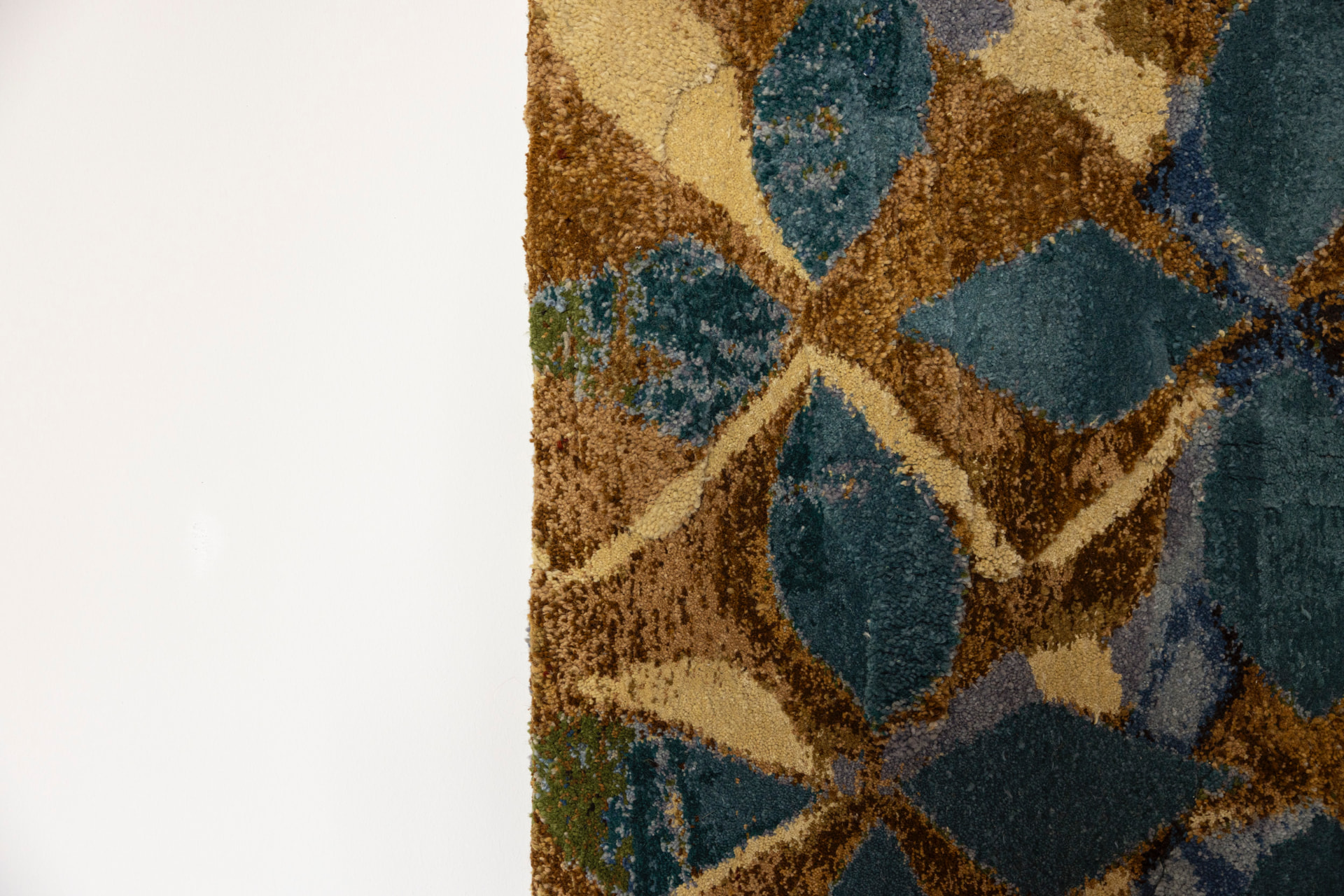 Close-up of a woven wall textile with blue, gold and brown diamond pattern