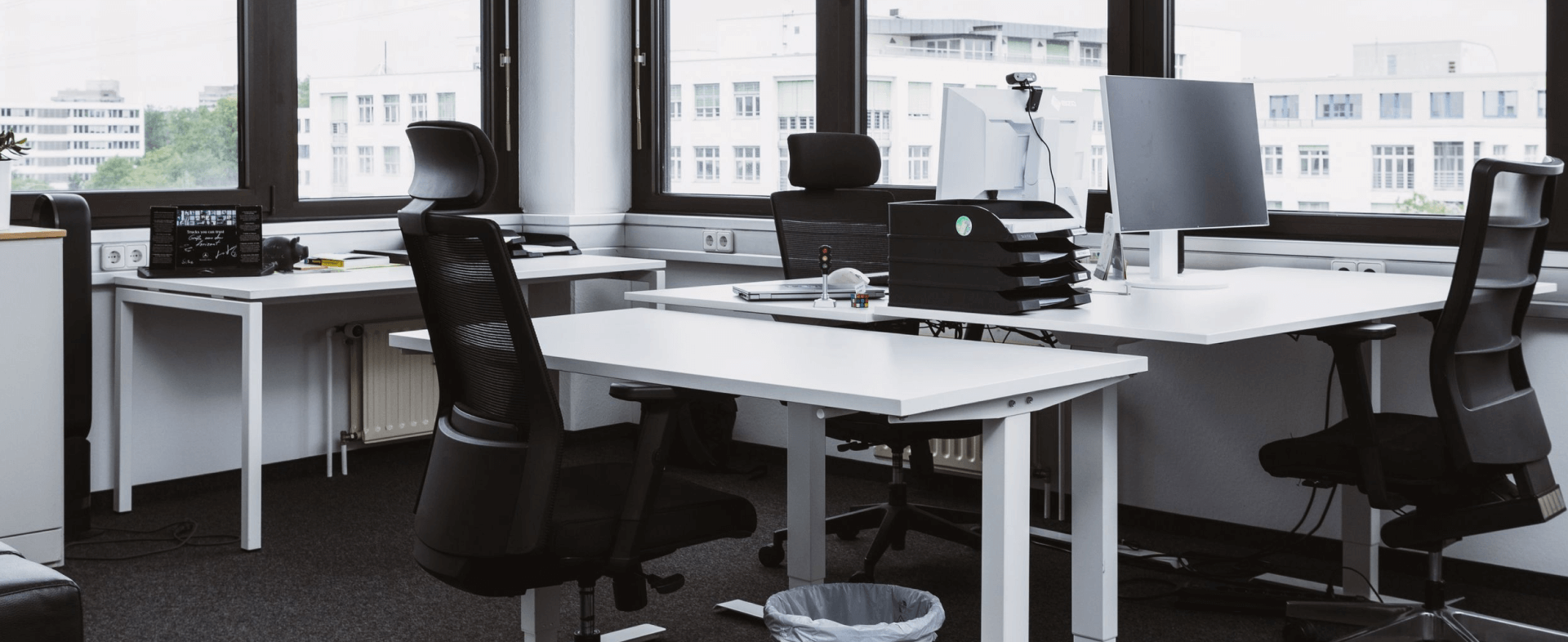 Bright private office with white desks, black chairs and large windows