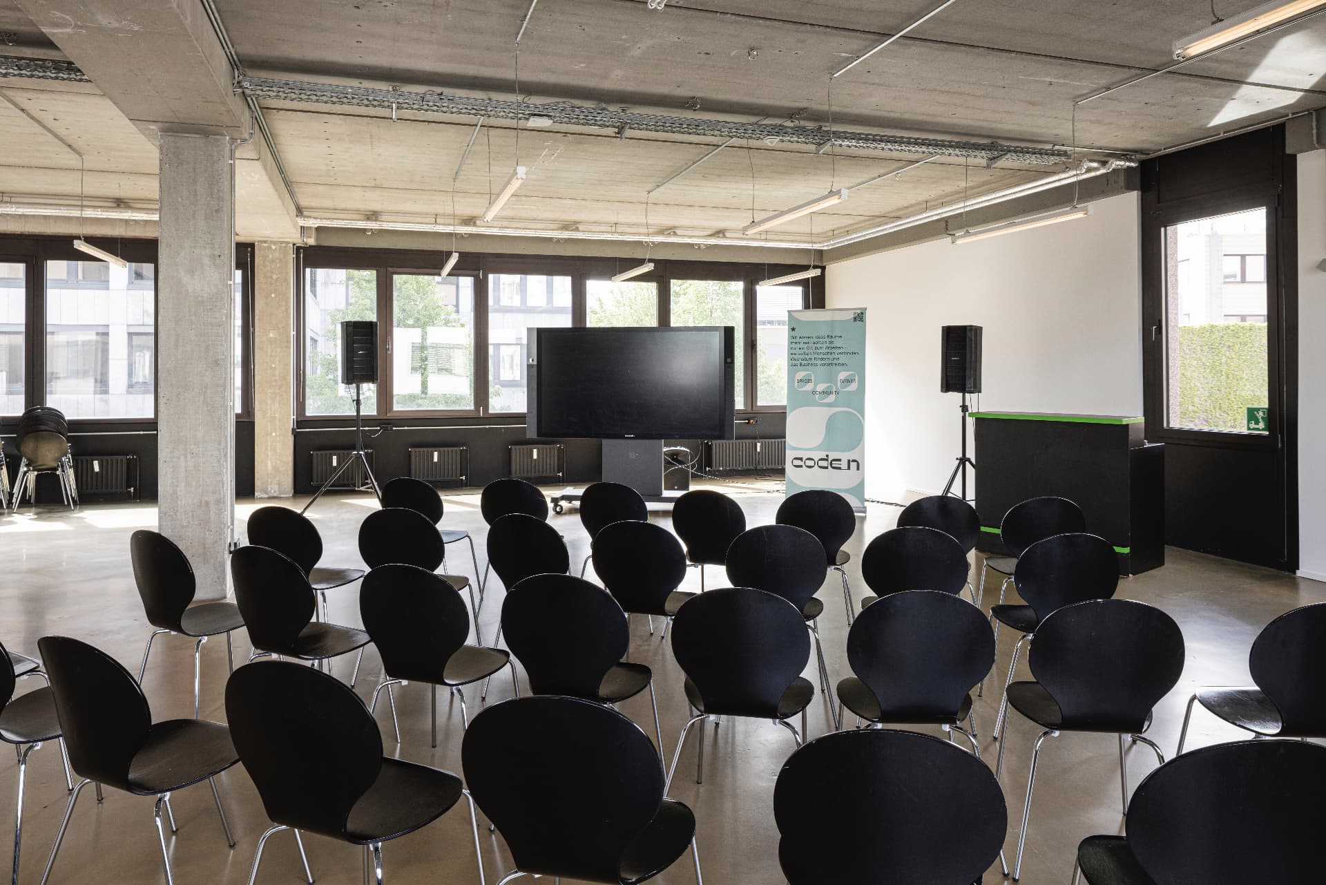 Event hall with black chairs facing a large screen