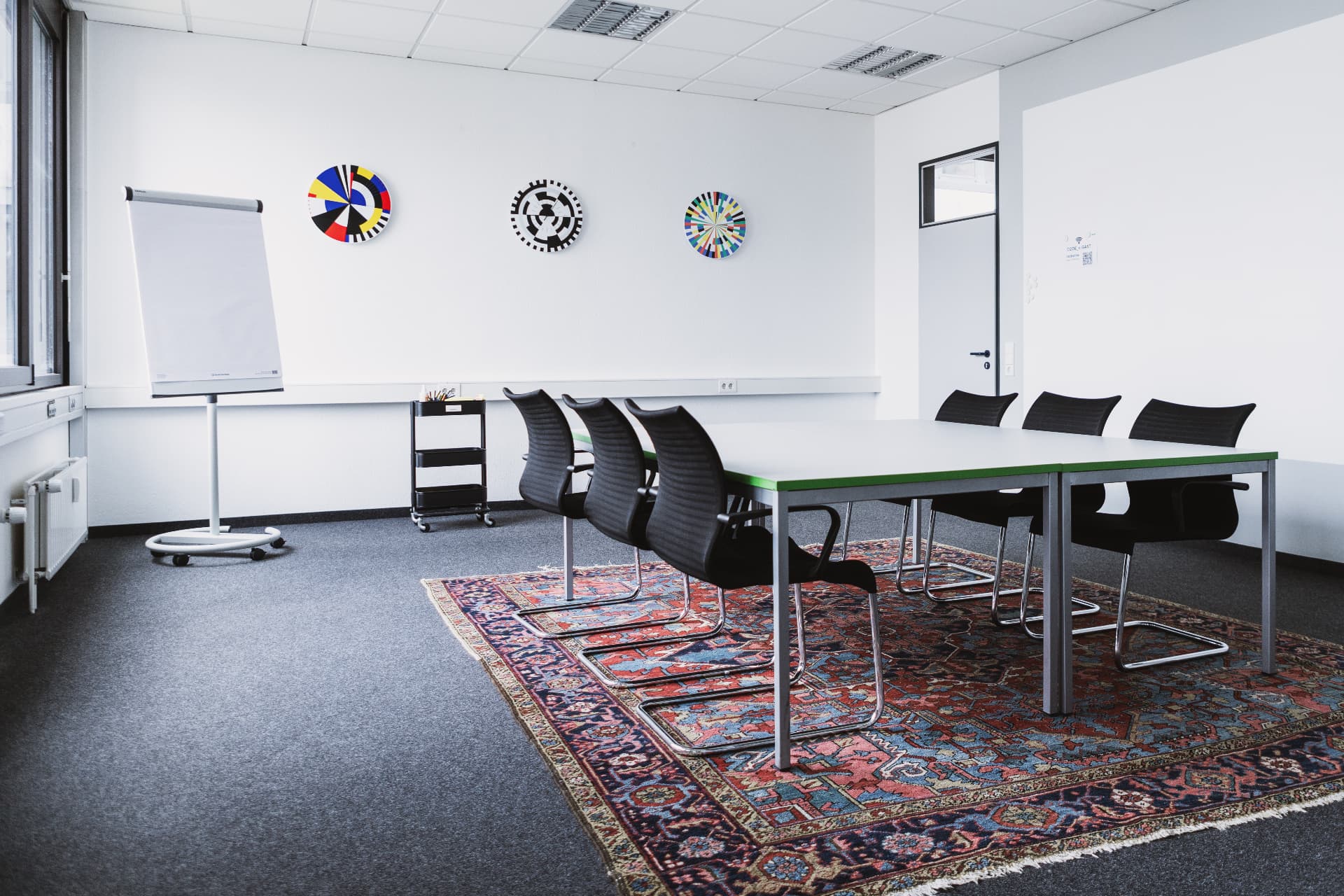 Boardroom with white table, black chairs and colorful wall art
