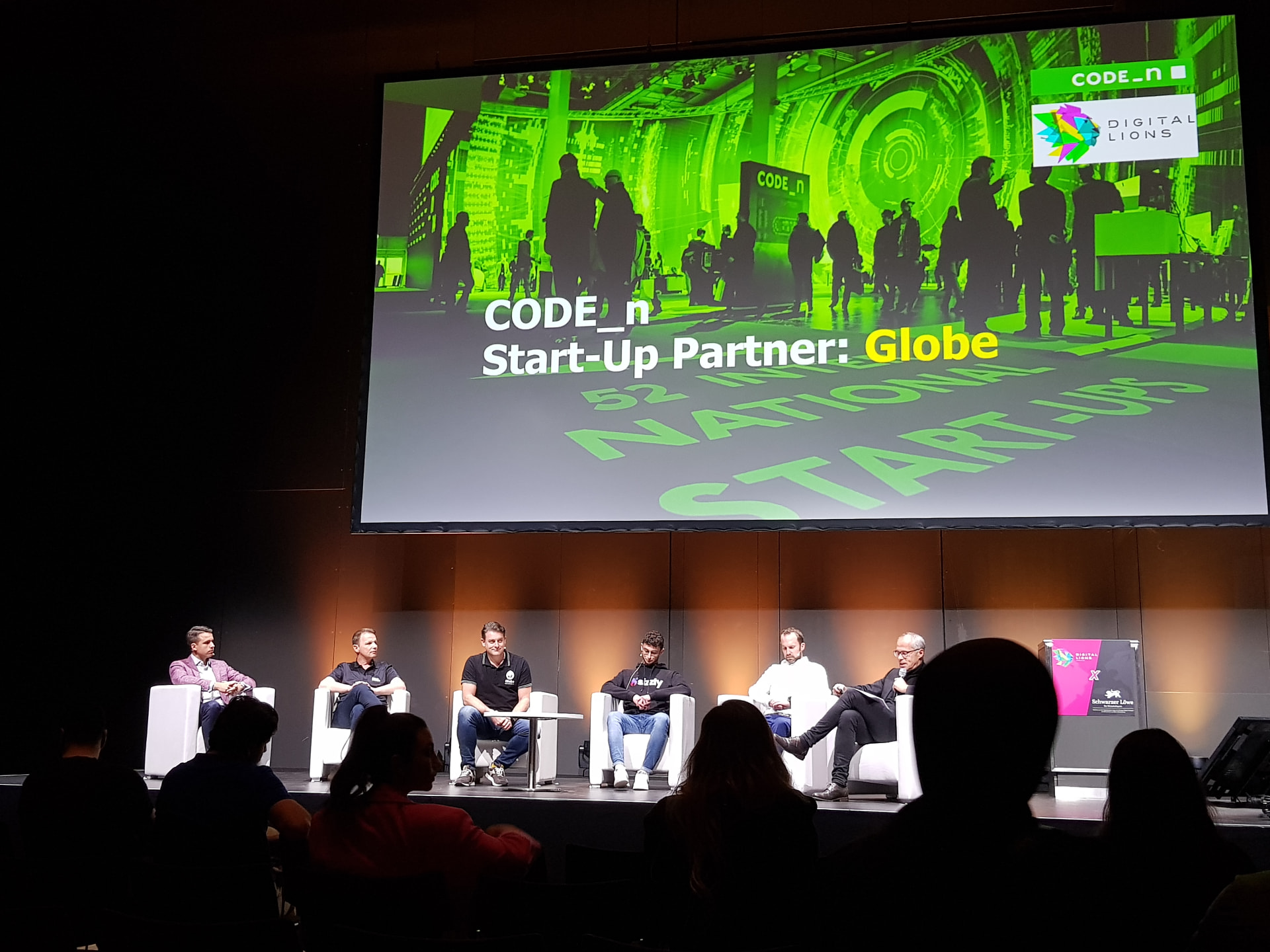 Panel discussion on stage in front of a large code_n screen